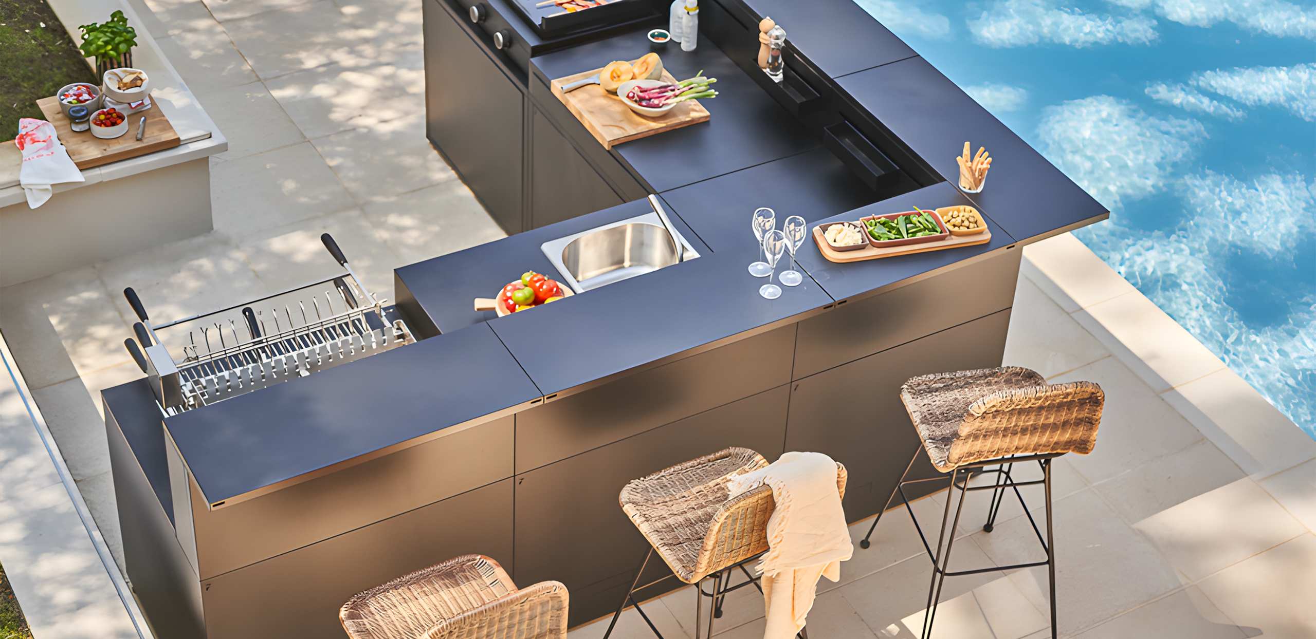 Cuisine extérieure Forge Adour avec plancha, évier et comptoir bar, aménagée au bord d’une piscine sur une terrasse contemporaine.