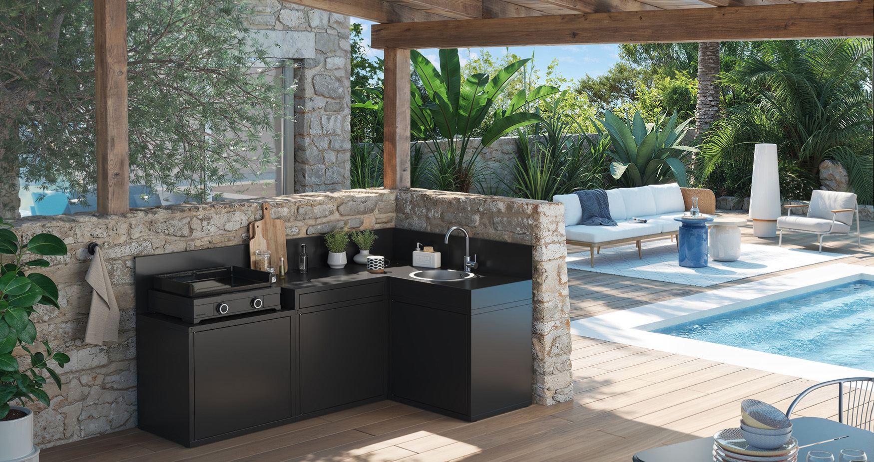 Cuisine extérieure noire Forge Adour avec plancha et évier, intégrée sous une pergola en bois au bord d’une piscine.