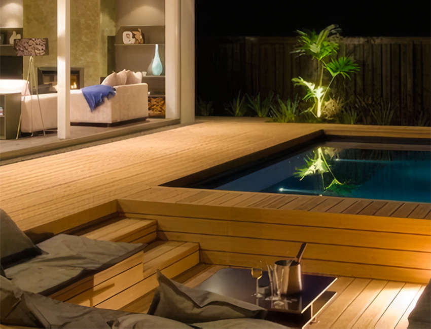 Terrasse en bois avec piscine et éclairage extérieur de nuit