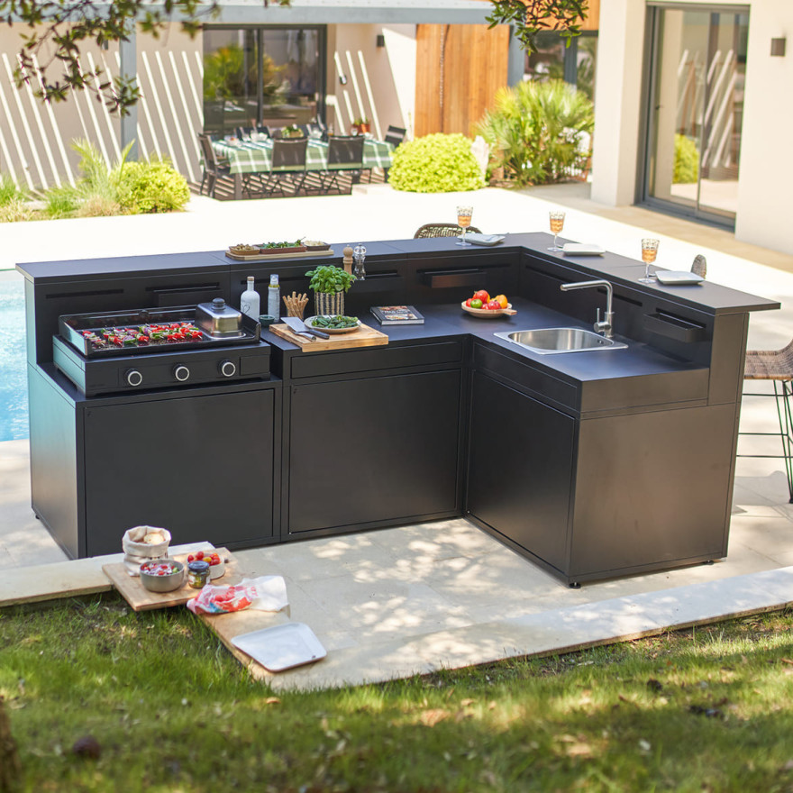 Cuisine extérieure Forge Adour en configuration quatre modules avec plancha, évier et rangements, installée dans un jardin contemporain.