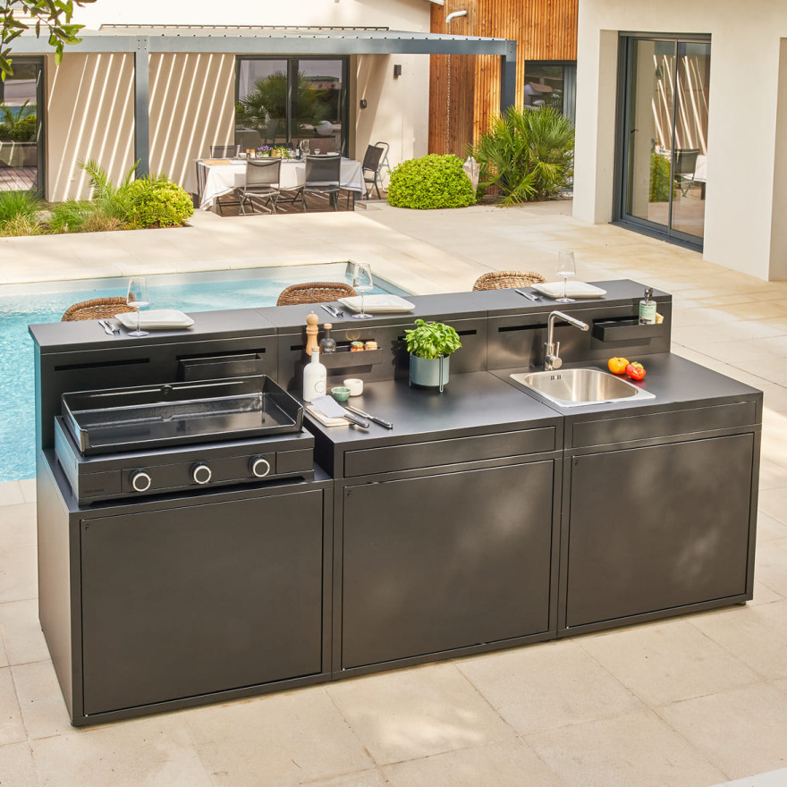 Cuisine extérieure Forge Adour avec plancha, évier et rangements, composée de trois modules installés au bord d’une piscine.